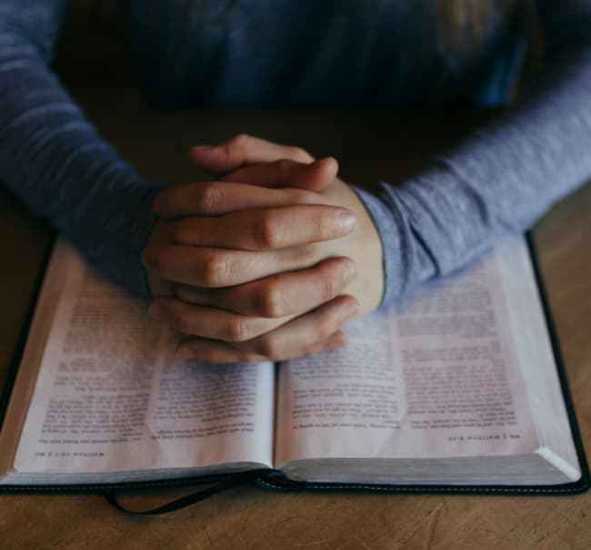 Manos en oración sobre la Biblia